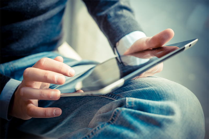 Nahaufnahme: zu sehen die Hände eines Mannes, der ein Tablet hält.