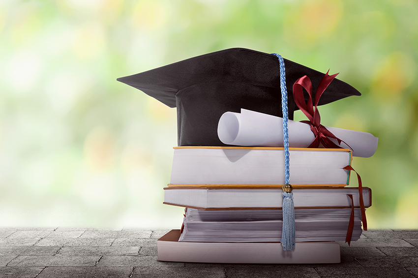 Stack of books with diploma and graduation cap