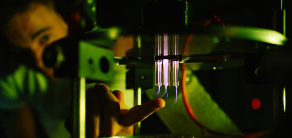 Ein junger Forschender vor einem Plasma