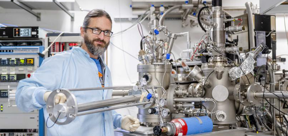 KM_Arne Ludwig_Teilchenbeschleuniger Arne Ludwig an der Molekularstrahlepitaxie-Anlage der Ruhr-Universität Bochum, mit der er das Elektronengas erzeugt. die Molekularstrahlepitaxie-Anlage sieht futuristisch aus: glänzender Chrom, viele Kabel und Ventile.