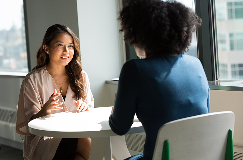 Zwei Frauen unterhalten sich an einem weißen Tisch